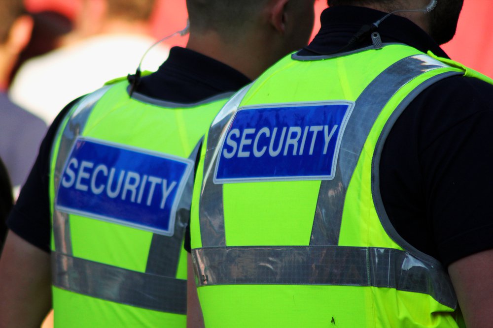 Image of two male security Guards with bright tops on. 