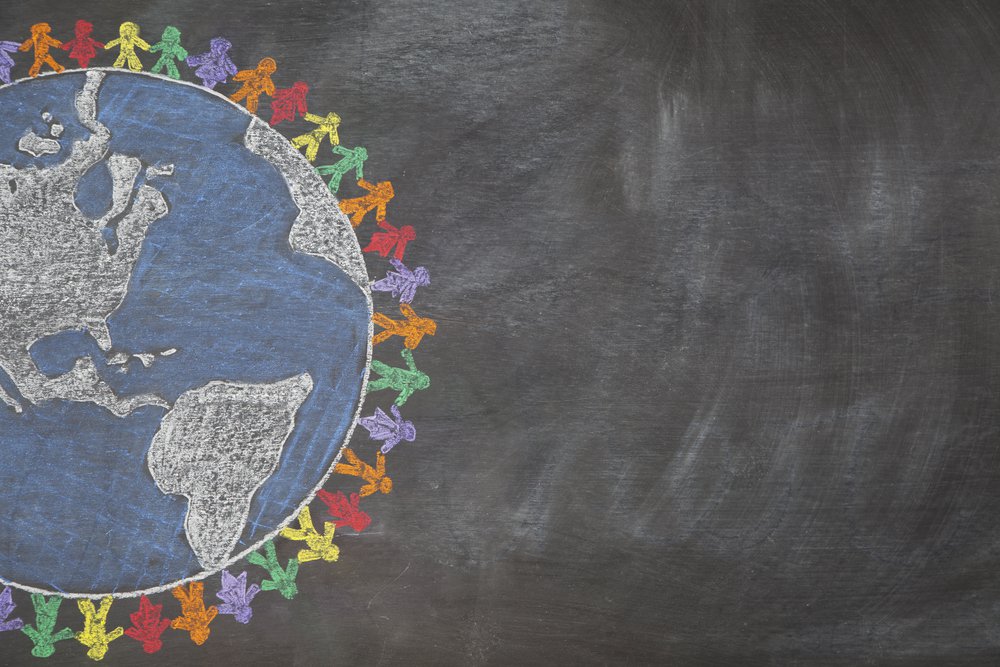 A hand drawn chalkboard shows multi-ratial people holding hands around the world to show care for the earth, peace, and unity. Shown off centered for copy-space. 